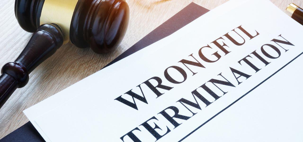 A document titled "Wrongful Termination" is placed next to a judge's gavel on a wooden surface. The image suggests a legal context, possibly relating to employment law or legal proceedings involving disputes over job termination.