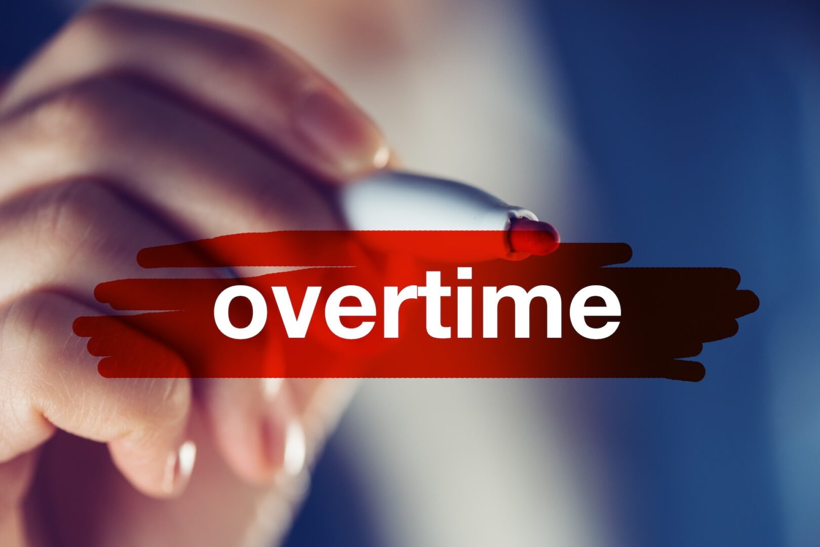 A hand holding a marker appears to draw a red line over the word "overtime" in white text against a blurred background.