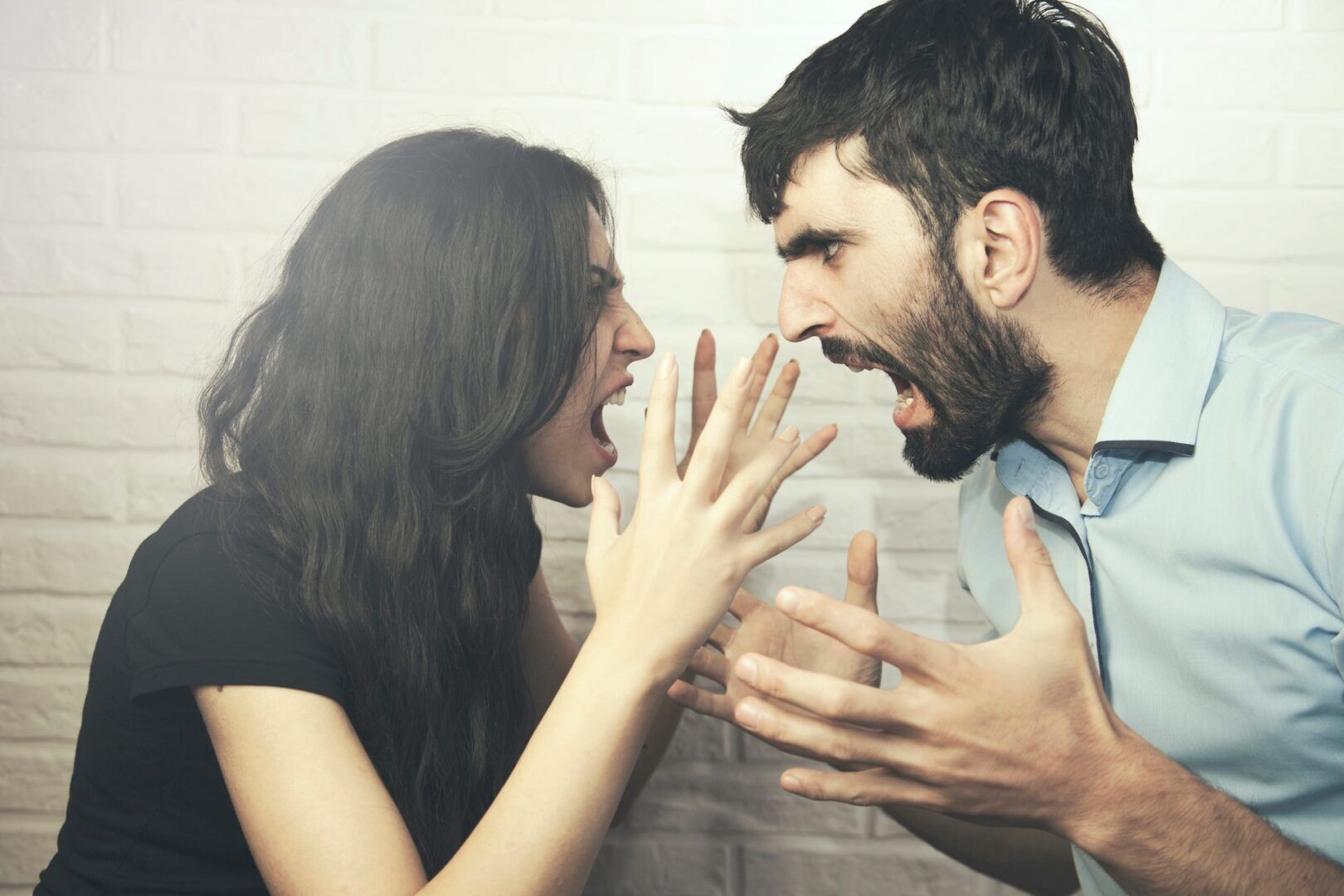 A woman and a man face each other, both shouting with angry expressions and raised hands, appearing to be in a heated argument—a scene that could prompt questions about when and how to file for a divorce modification in West Virginia.