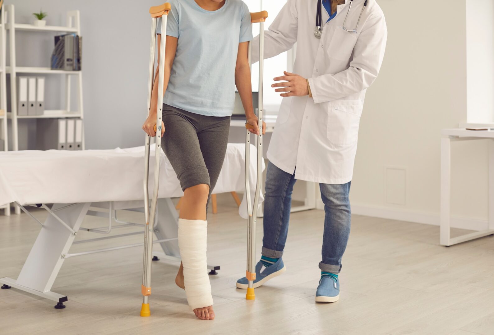 A person with a cast on their lower leg uses crutches in a medical office while a doctor offers support, highlighting situations where you might wonder: What injuries require a personal injury lawyer? Know when to call an attorney for help. A person with a cast on their lower leg uses crutches in a medical office while a doctor offers support, highlighting situations where you might wonder: What injuries require a personal injury lawyer? Know when to call an attorney for help.