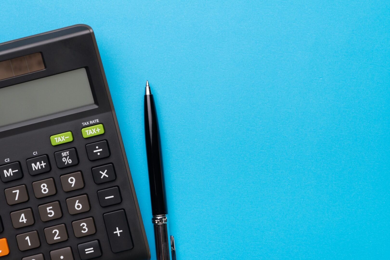 A black calculator and a black pen, perfect for Ohio child support calculations 2026, are placed side by side on a bright blue background, with ample empty space on the right.