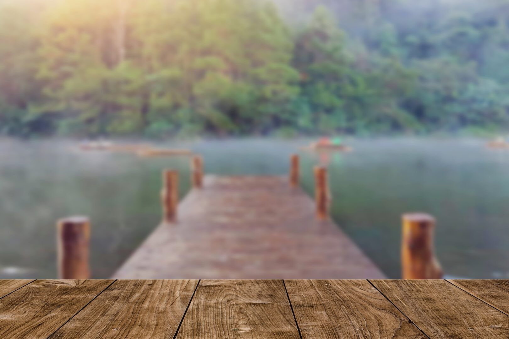 A wooden dock extends over a calm lake, surrounded by blurry trees in the background. The peaceful, misty atmosphere suggests a perfect spot to reflect on summer custody schedules amid nature’s quiet embrace.