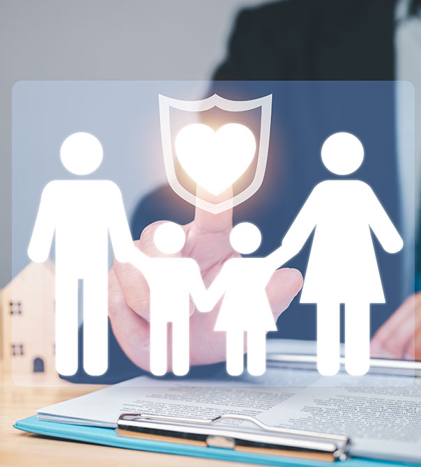 A person in a suit touches a virtual screen showing icons of a family, a shield, and a heart, symbolizing family protection or insurance. Papers and a pen are on the desk in the background.