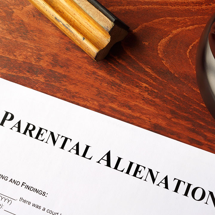 A document titled “Parental Alienation” on a wooden desk, partially visible, with a wooden stamp and part of a round object nearby.