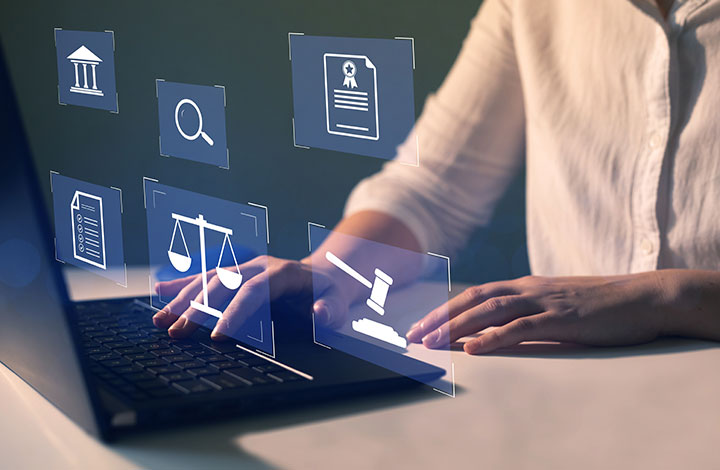Person typing on a laptop with virtual legal icons displayed, including scales of justice, a gavel, a magnifying glass, and official documents, representing online legal or law-related services.