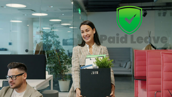 A smiling woman carrying a box of office supplies walks through a modern office; a green shield with a check mark and the words "Paid Leave" are displayed in the background. A man sits and works at a desk nearby.