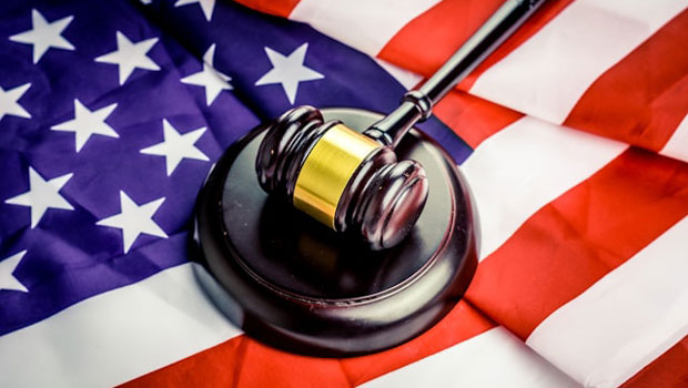 A judge’s gavel rests on a sound block atop a United States flag, symbolizing law and justice in America.