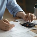 Person using a calculator with financial paperwork on a desk