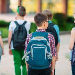 Children walking to school together with backpacks