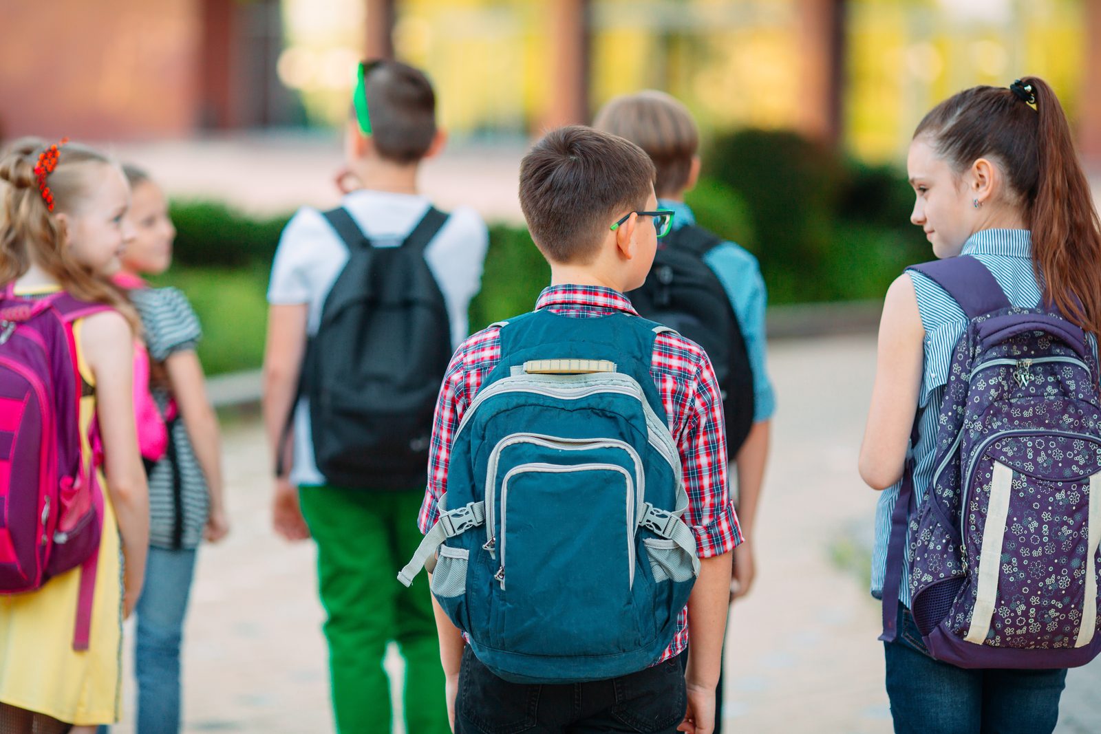 Children walking to school together with backpacks