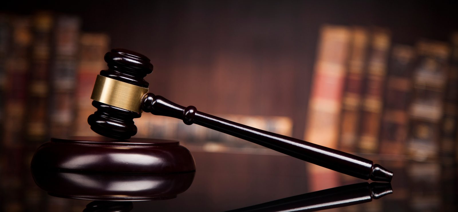 A judge's wooden gavel resting beside law books