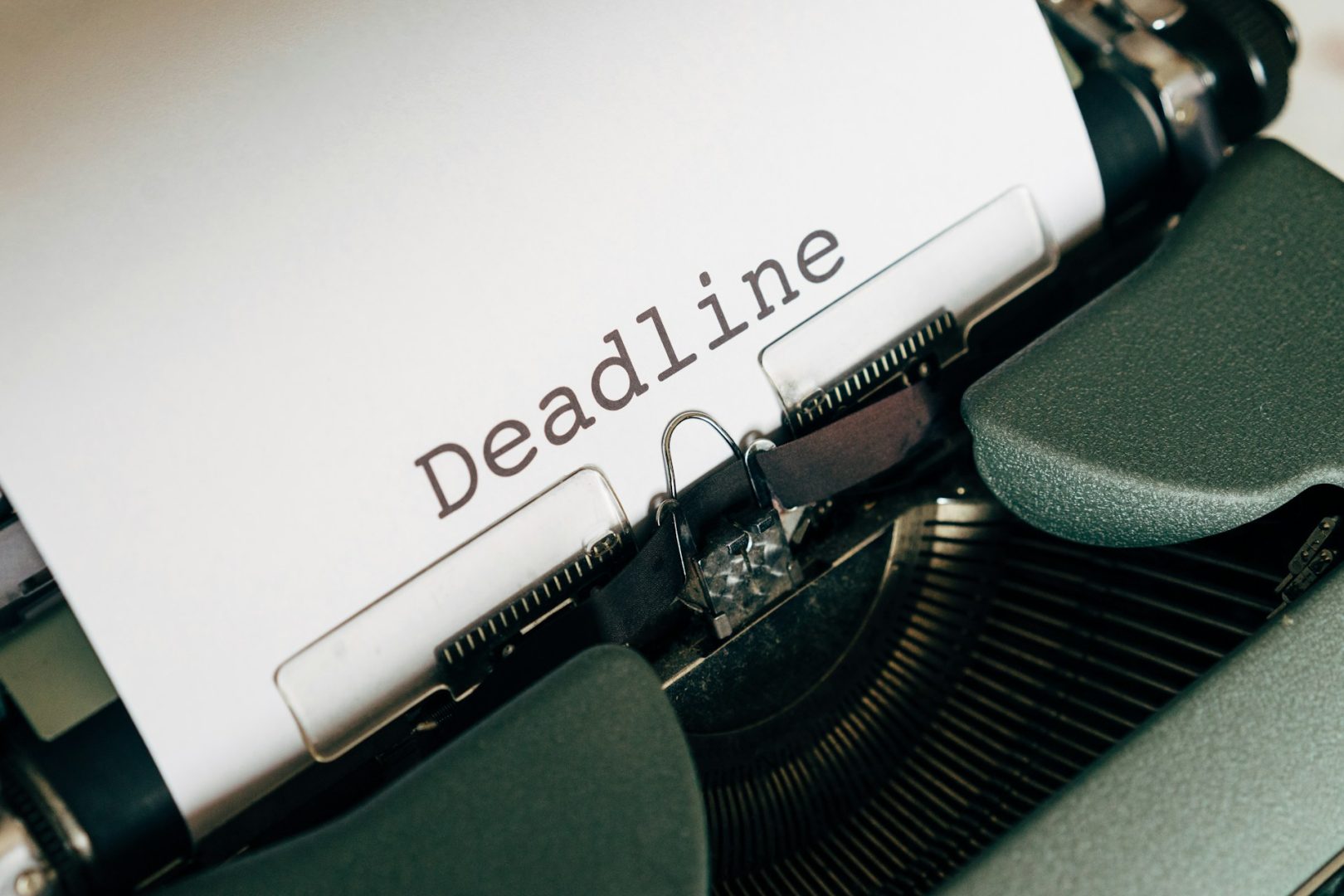 A close-up of a typewriter with a sheet of paper displaying the word "Deadline" typed on it in black letters.