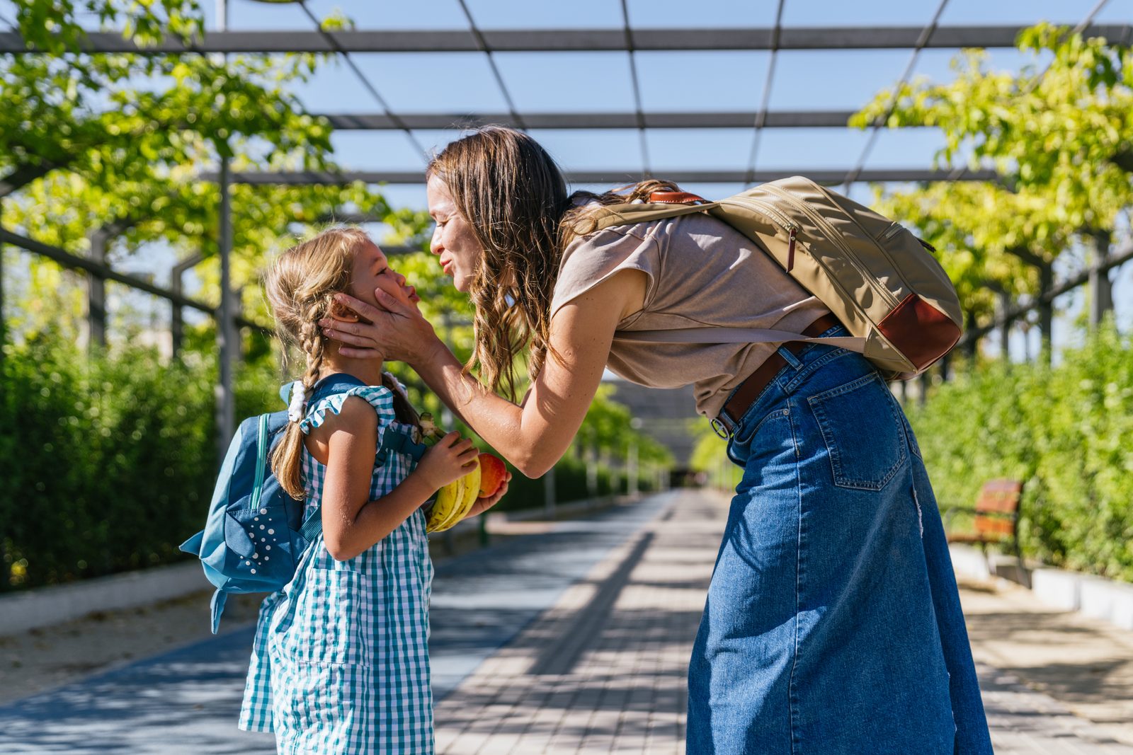 Mother showing affection to her young daughter outdoors