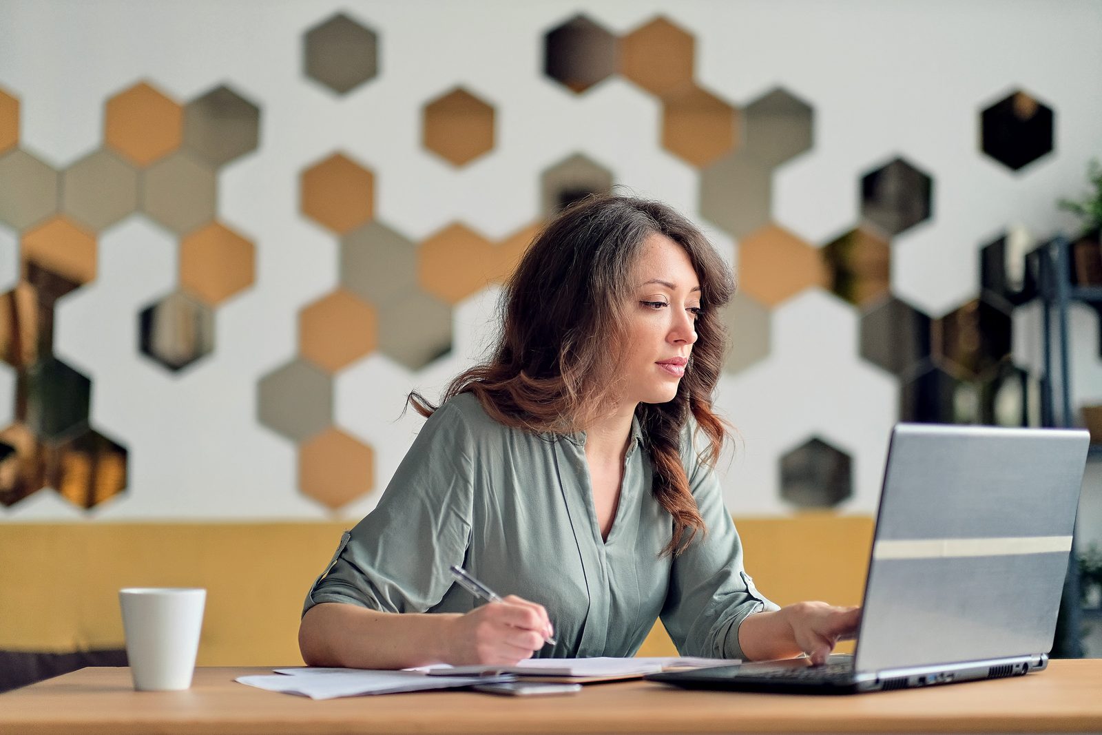 Parent using a laptop at a home desk with paperwork