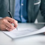 Person signing a noncompete agreement with a pen