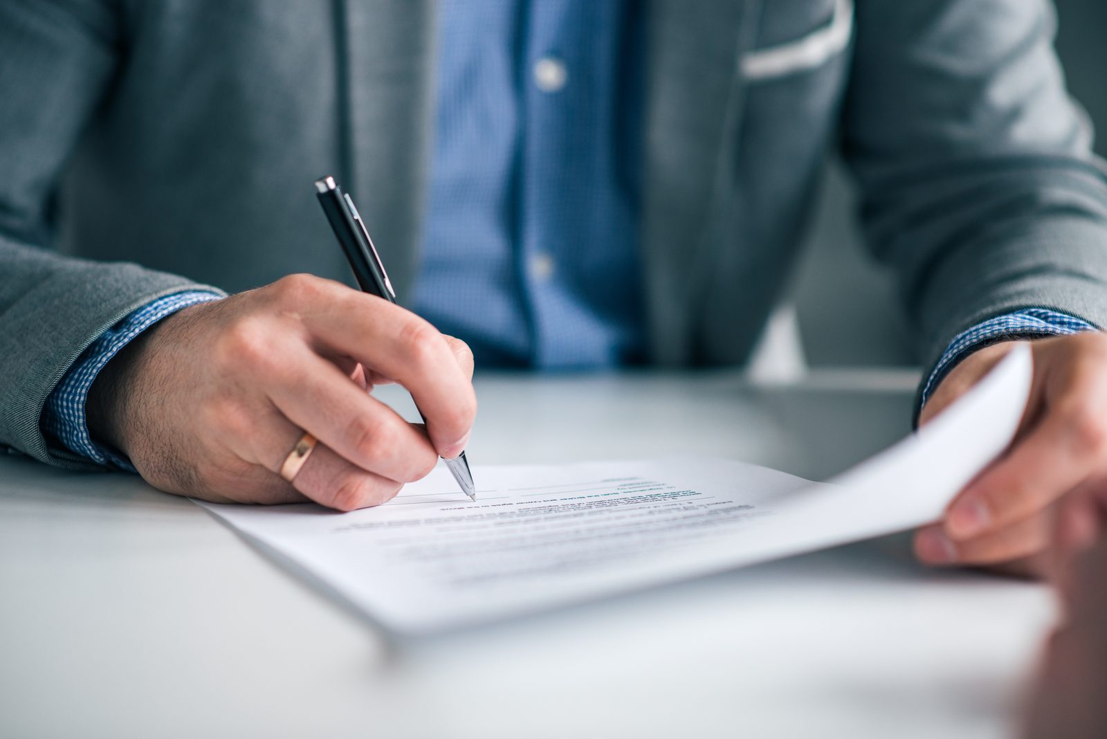 Person signing a noncompete agreement with a pen