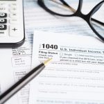 US 1040 income tax form with a calculator and pen
