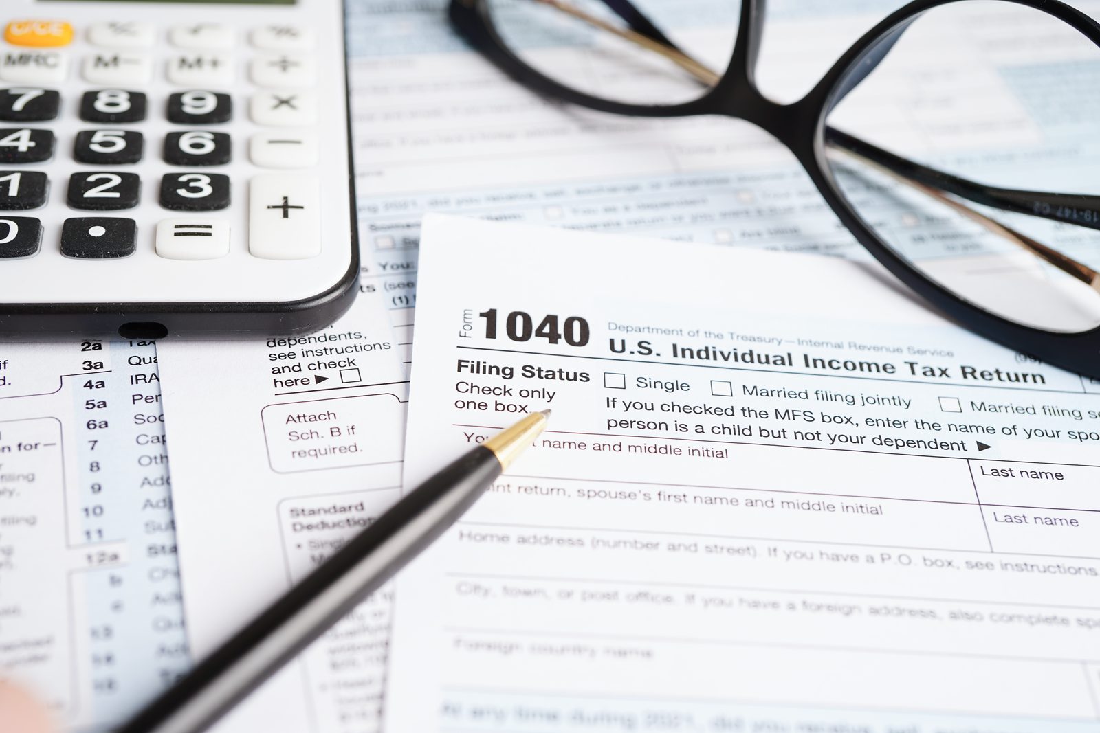 US 1040 income tax form with a calculator and pen
