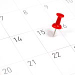 Red pushpin marking a date on a calendar