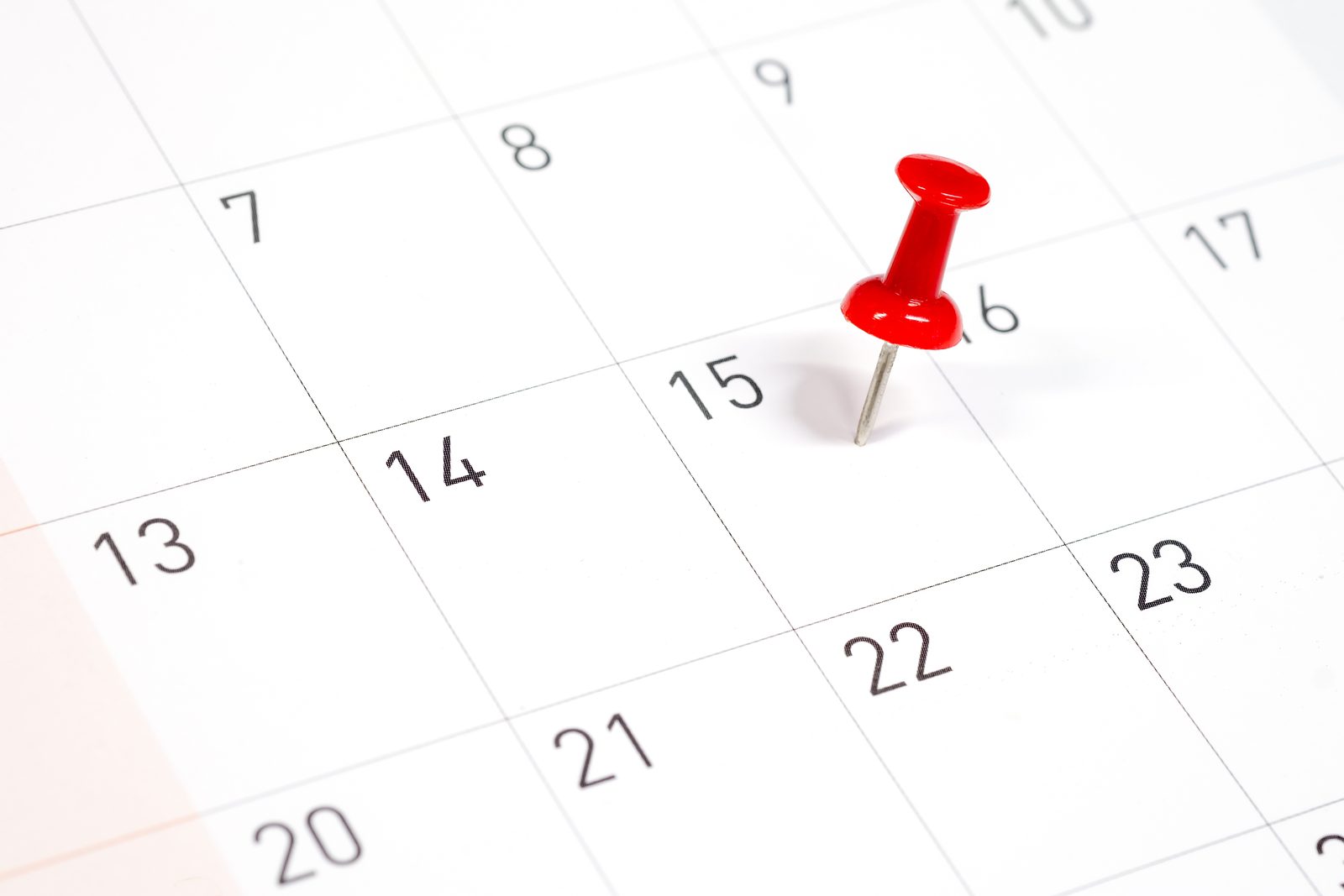 Red pushpin marking a date on a calendar