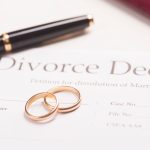 Wedding rings resting on a divorce decree beside a pen