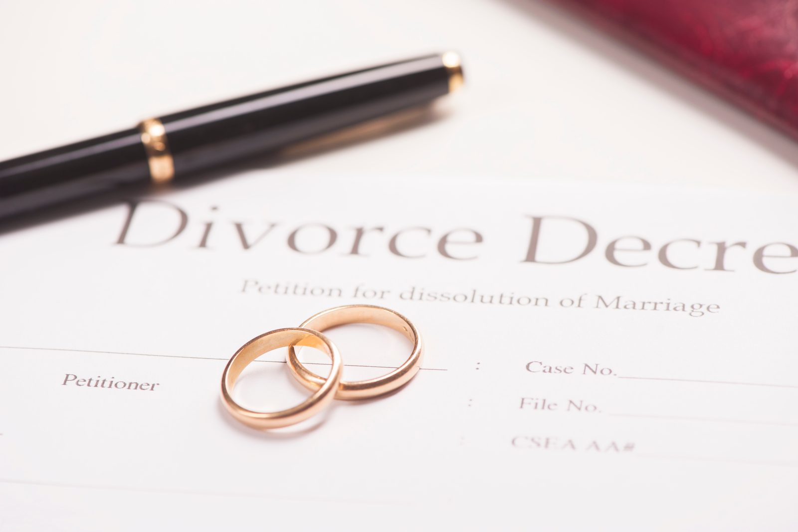 Wedding rings resting on a divorce decree beside a pen