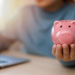 Parent holding a pink piggy bank while saving for a child's future