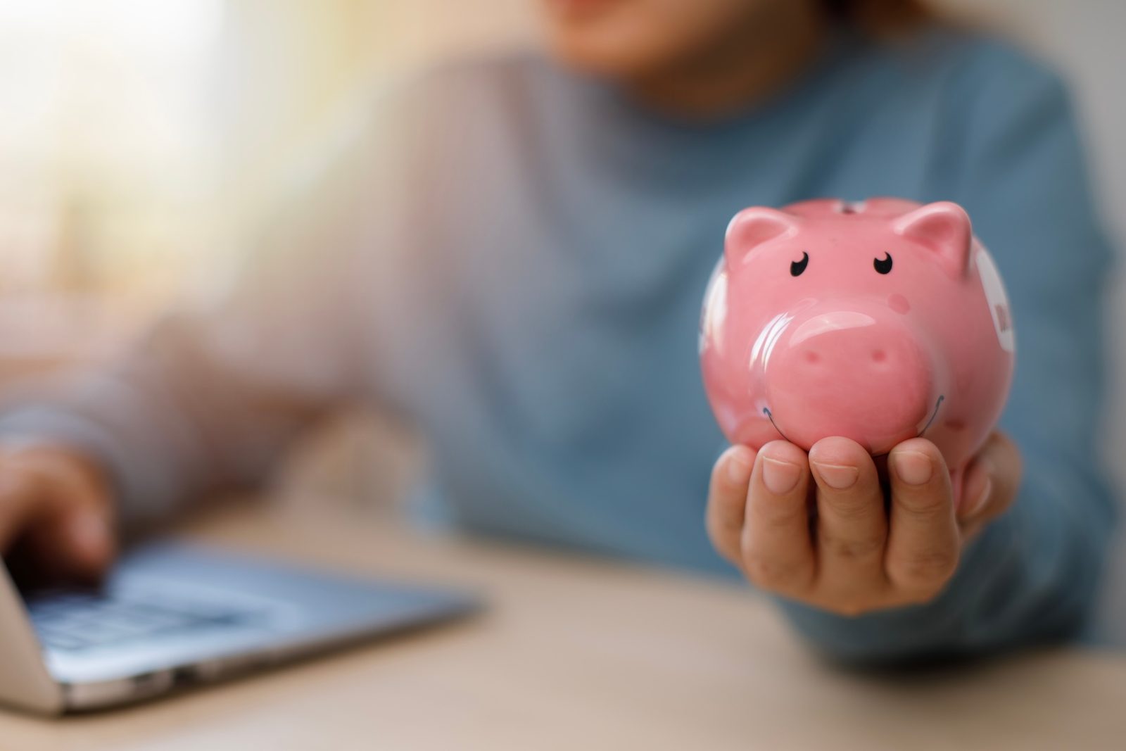 Parent holding a pink piggy bank while saving for a child's future