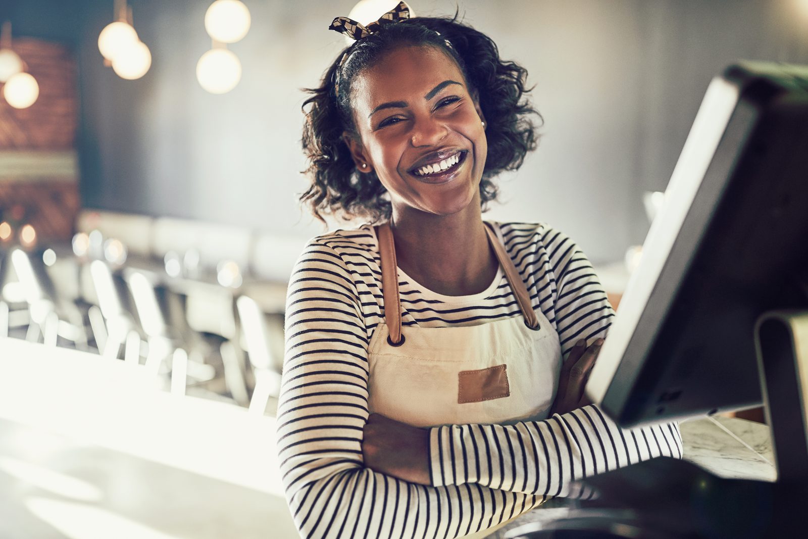 Smiling restaurant server in an apron standing at the register